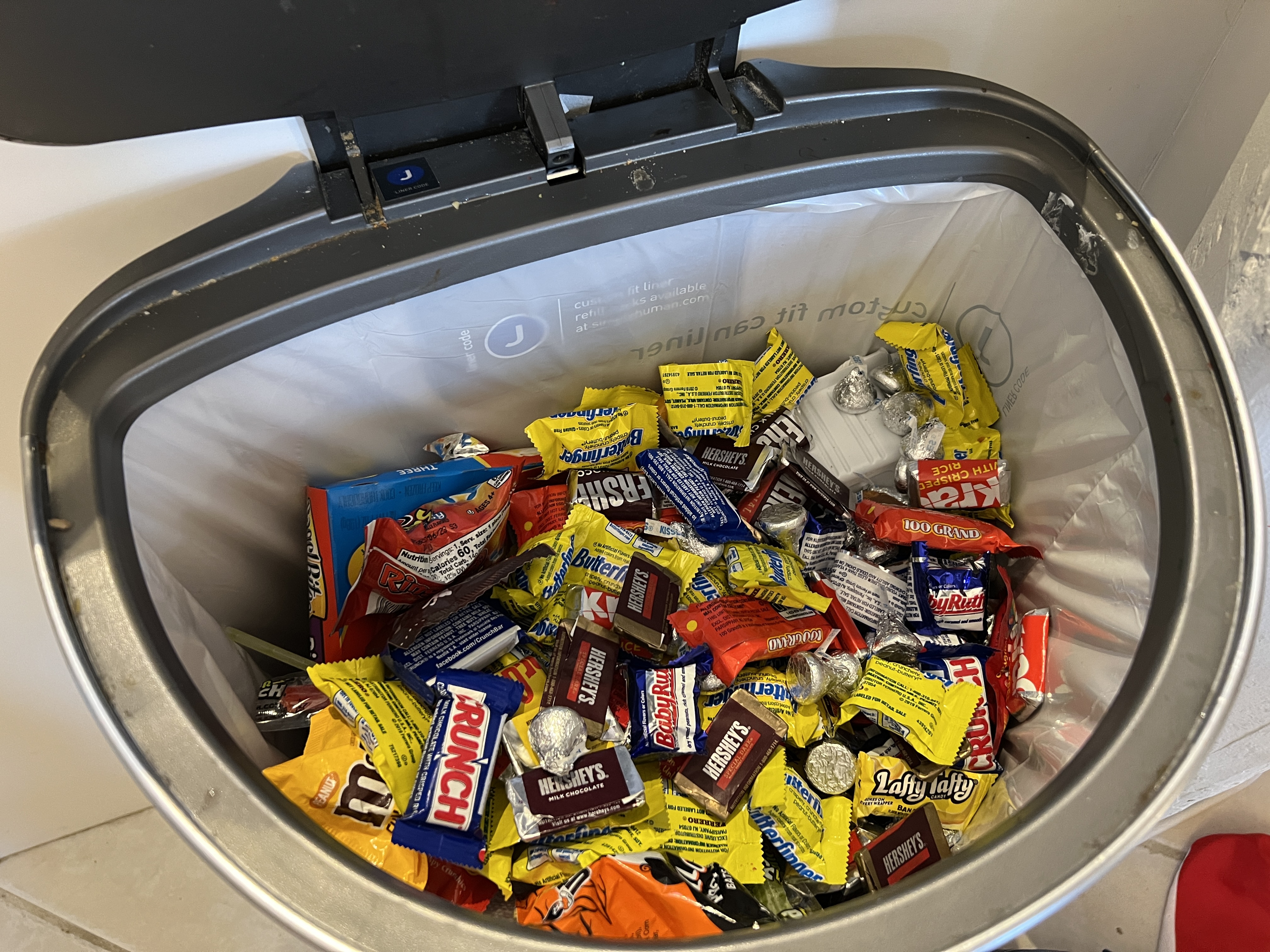 Discarded Halloween candy in a trash can.