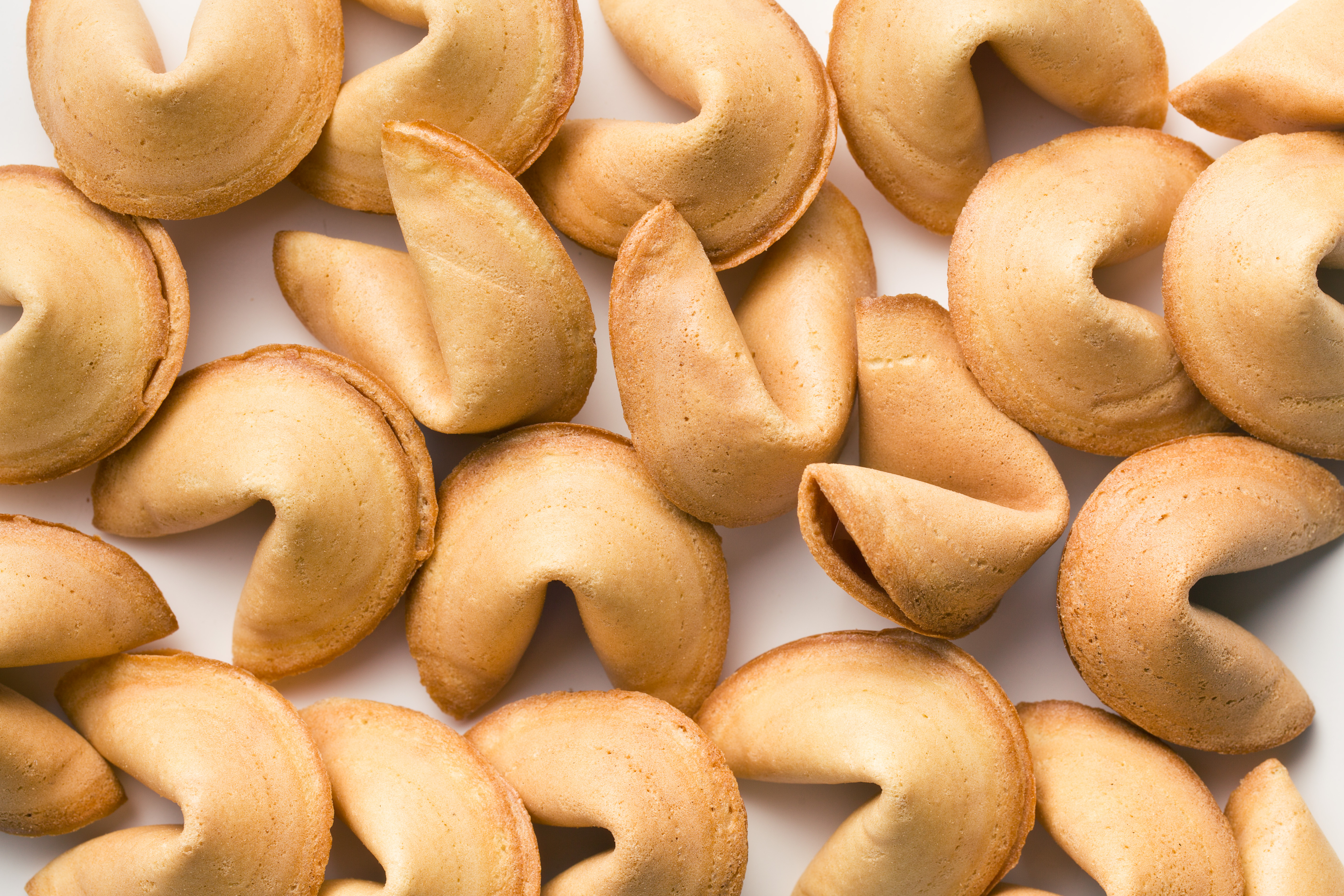 A pile of golden fortune cookies on a white background.