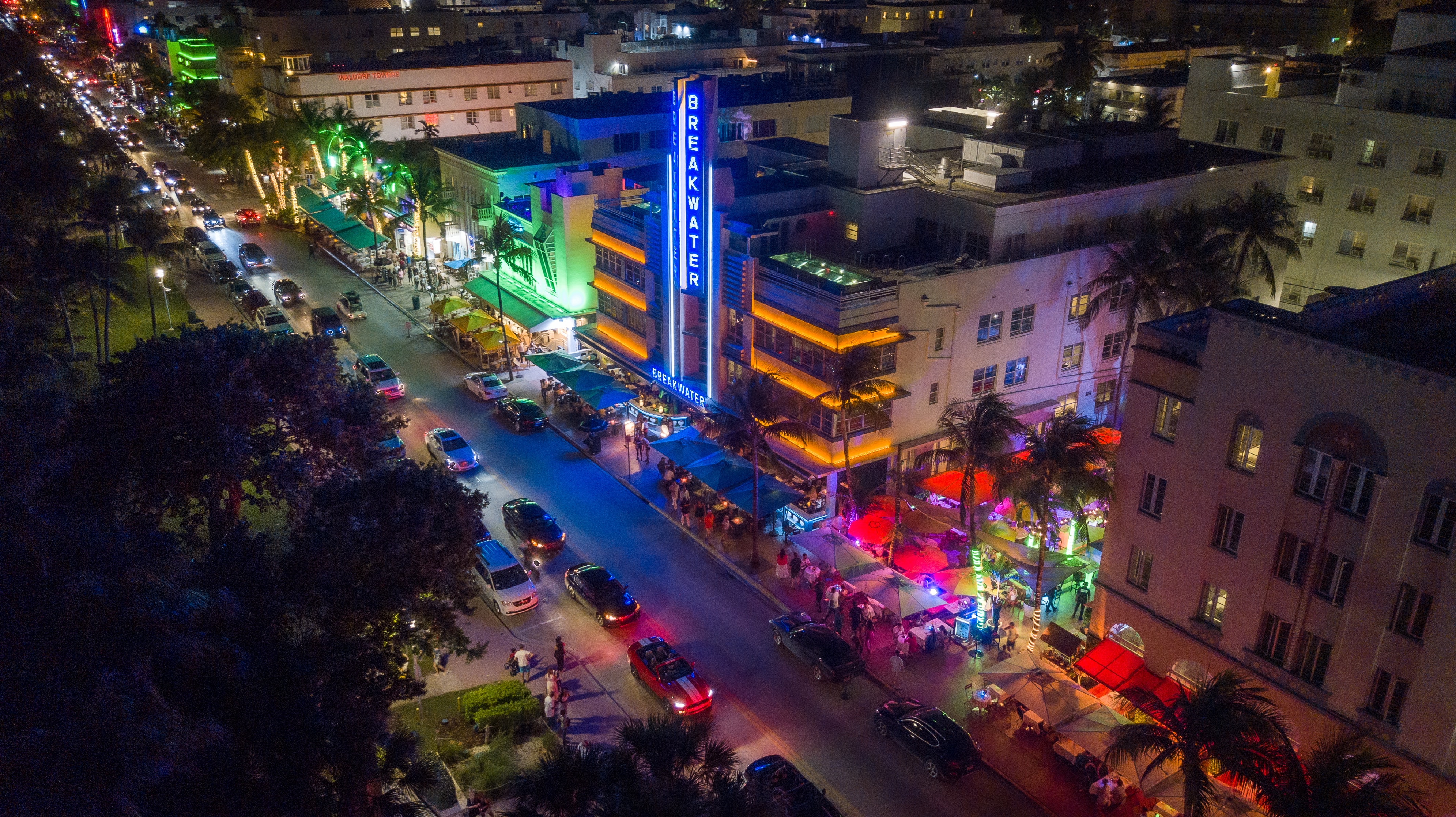 Aerial photo of Ocean Drive at night with bright colors and cars on the street