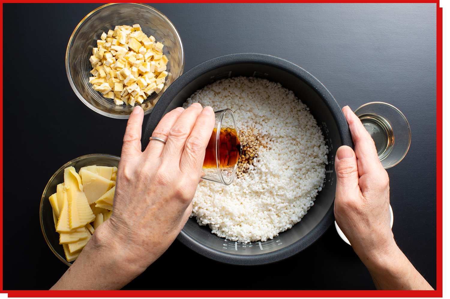 A person pours soy sauce into their rice cooker pot as they prepare to cook dinner.